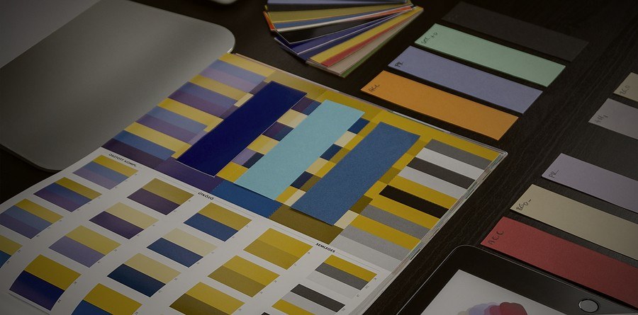 Color palette swatches and brand identity materials on a designer's desk, representing Parsian Holdings' branding and marketing work